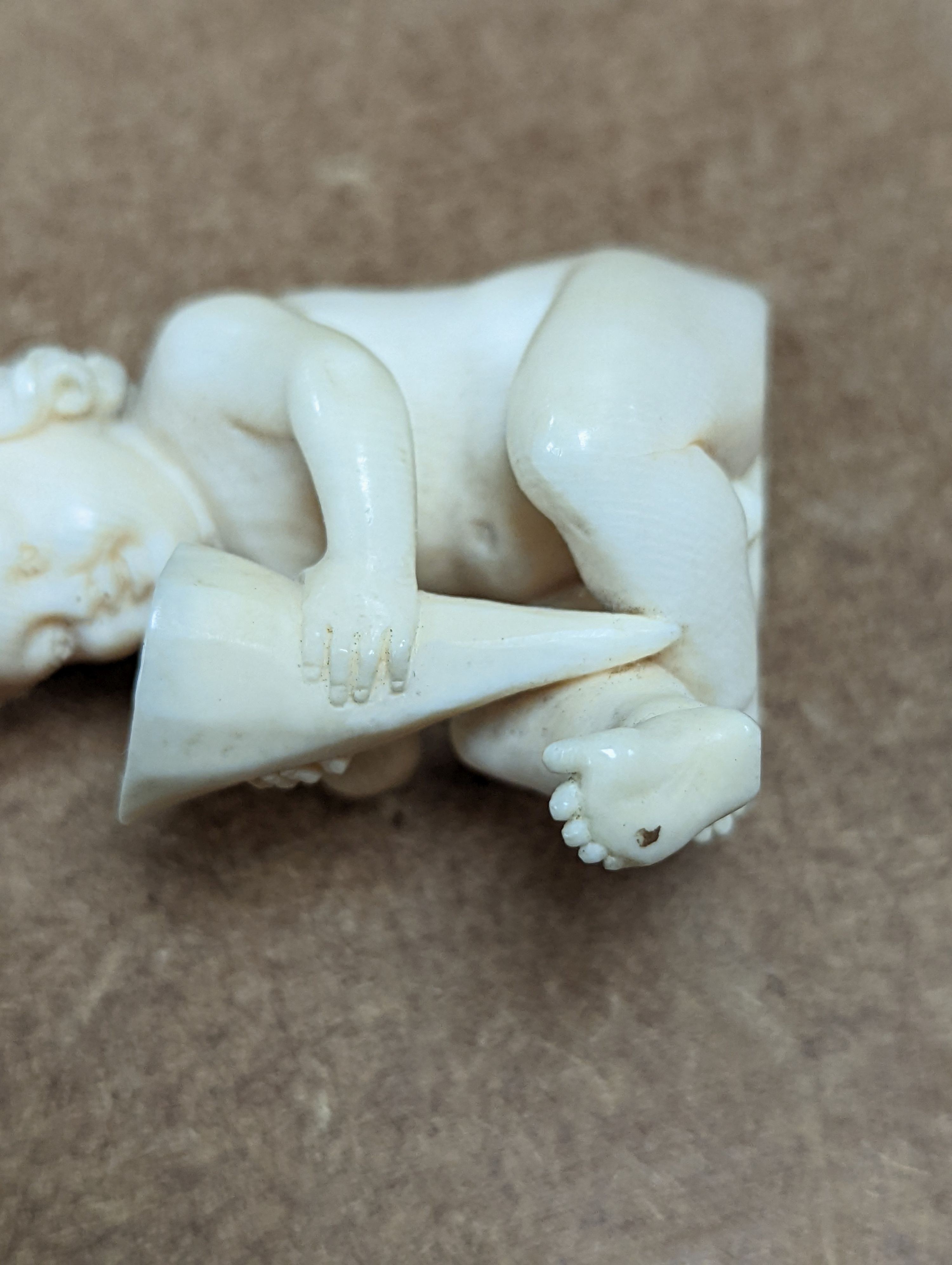 A 19th century Continental carved ivory figure of a child holding a cornucopia - 7cm tall